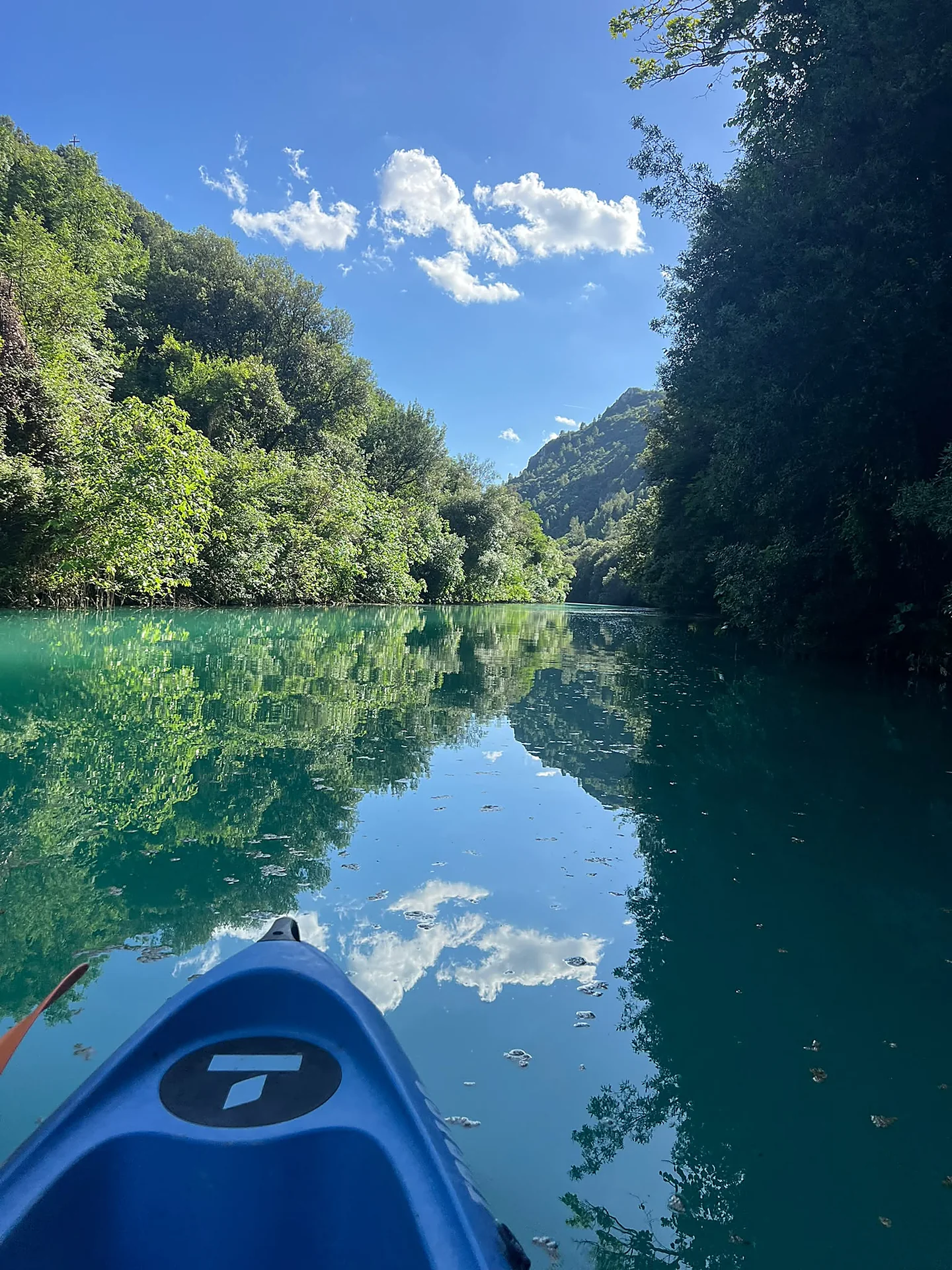 Panorama dalla canoa sulle Gole del Nera, acqua smeraldo riflette le montagne e il cielo azzurro