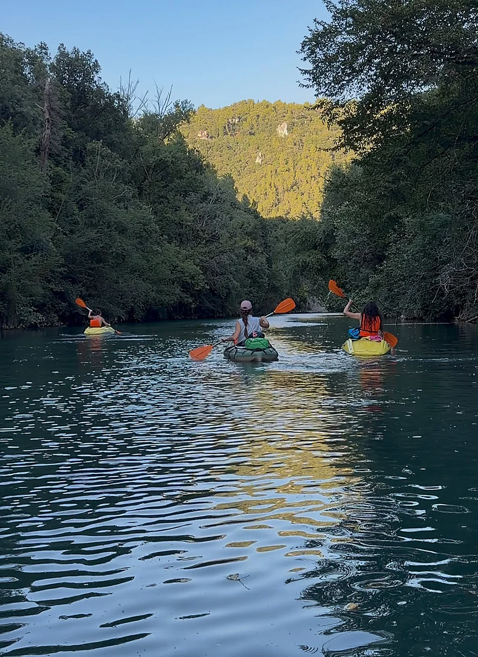 Tre canoe con famiglie pagaiano sul fiume Nera tra le gole verdi al tramonto